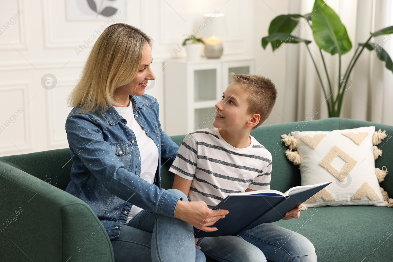 Photo of Mother and son reading book on sofa at home