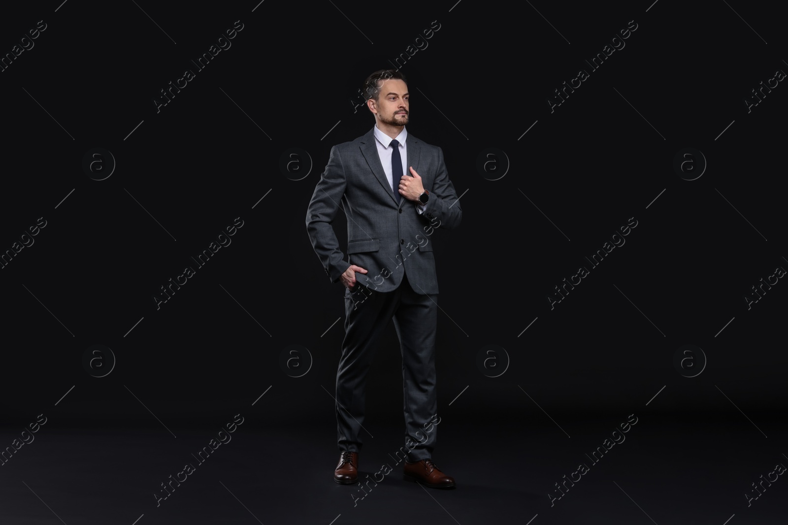 Photo of Confident man in classic suit on black background