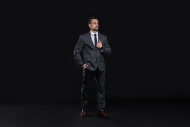 Photo of Confident man in classic suit on black background