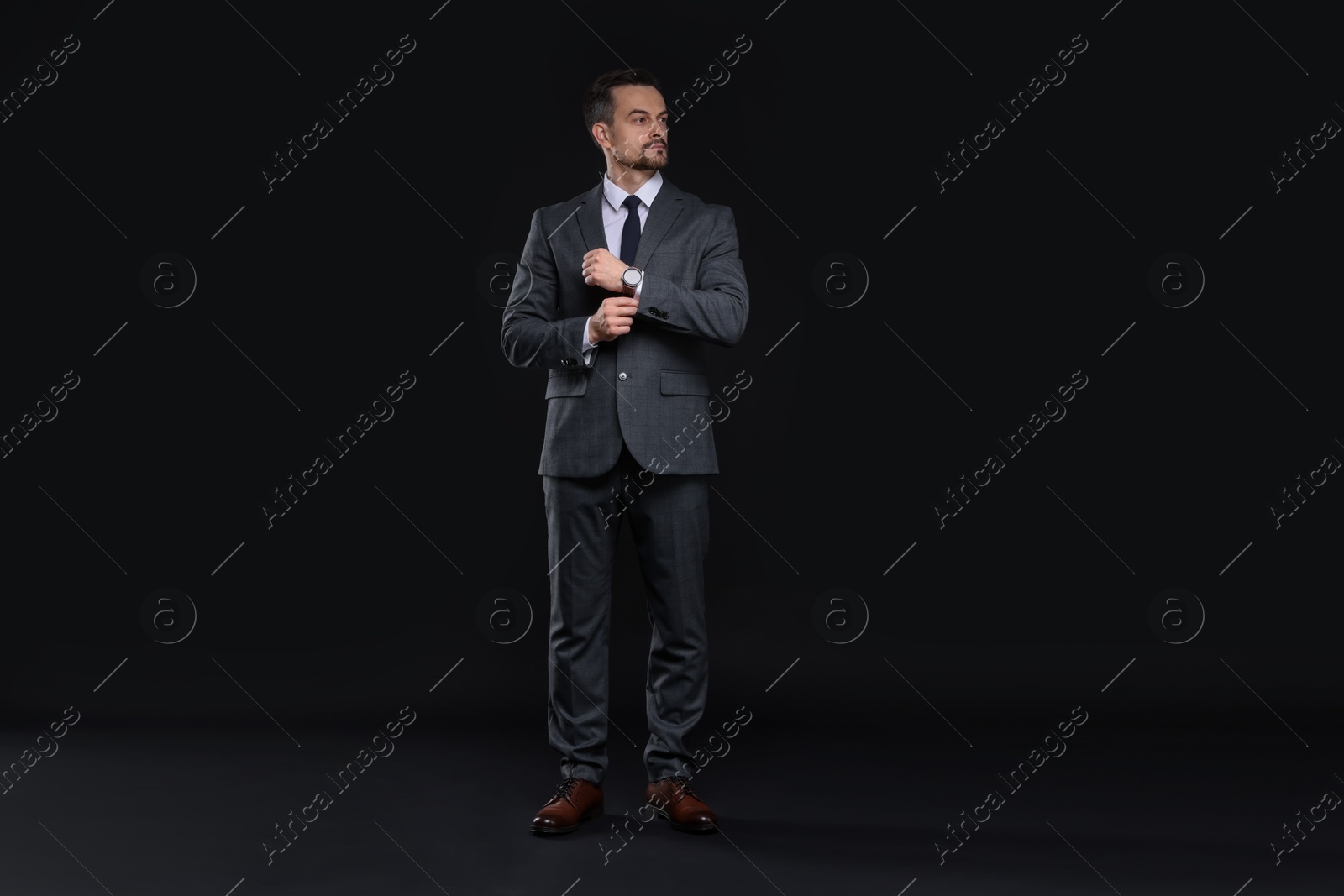 Photo of Confident man in classic suit on black background