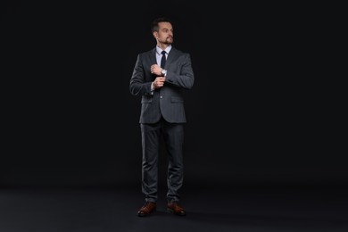 Confident man in classic suit on black background