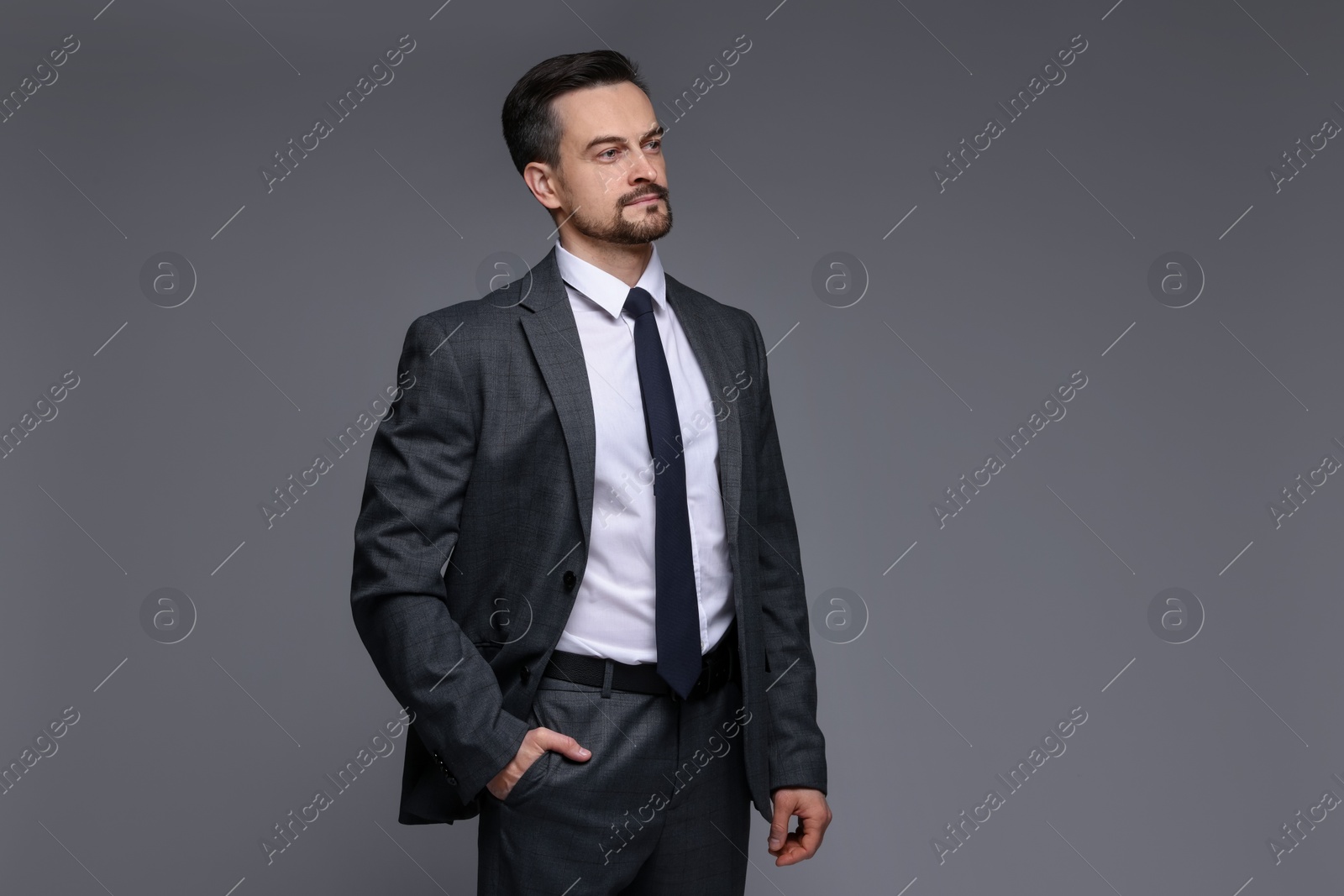 Photo of Confident man in classic suit on grey background. Space for text