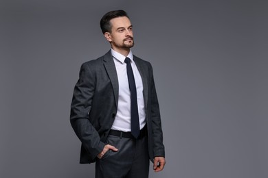 Photo of Confident man in classic suit on grey background. Space for text