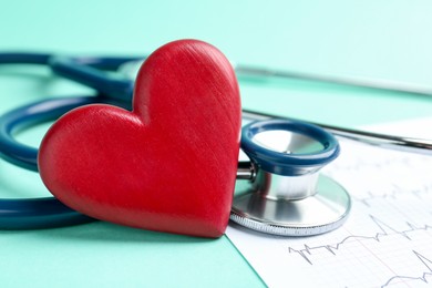 Photo of Cardiology. Stethoscope, cardiogram and red decorative heart on turquoise background, closeup