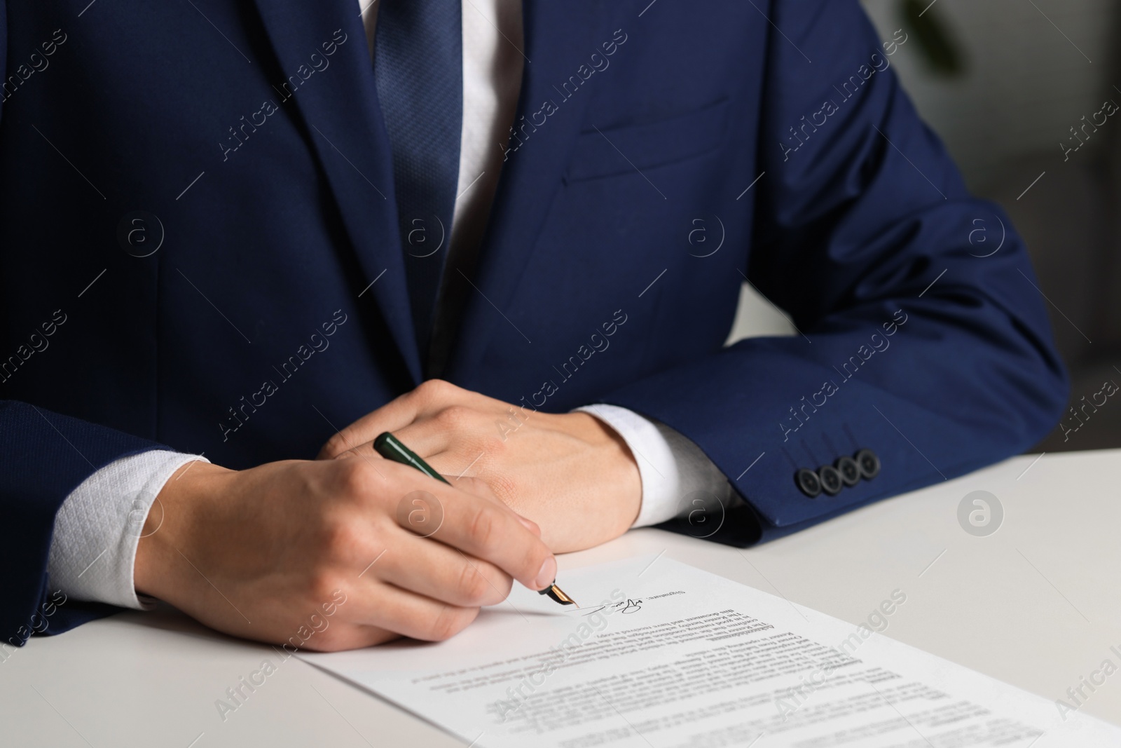 Photo of Man putting signature on document at white table, closeup