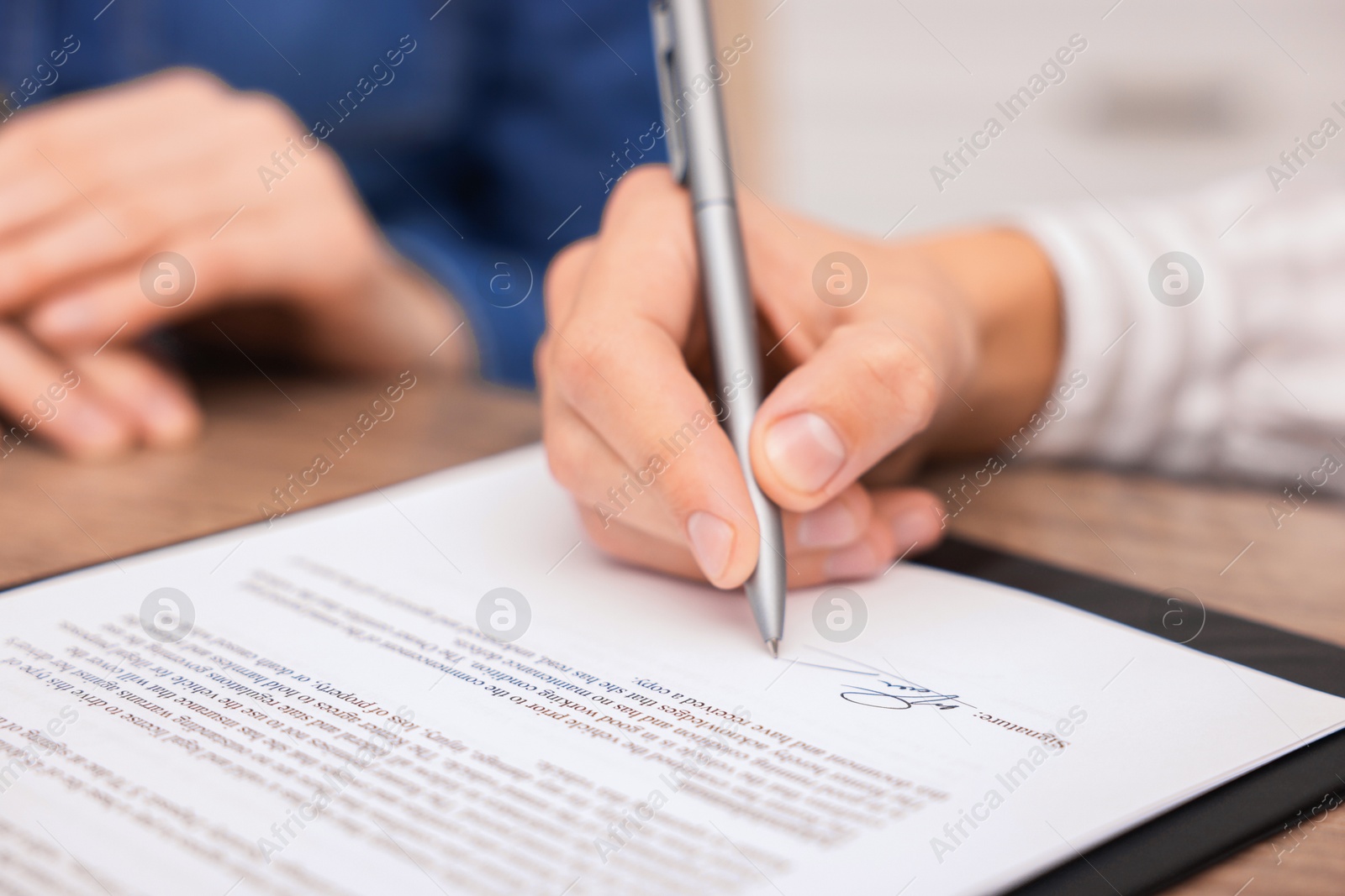 Photo of Man putting signature on document at table, closeup