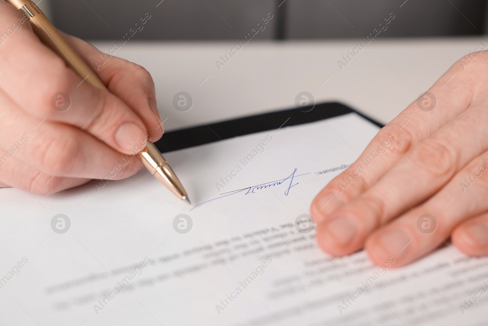 Photo of Woman putting signature on document at white table, closeup