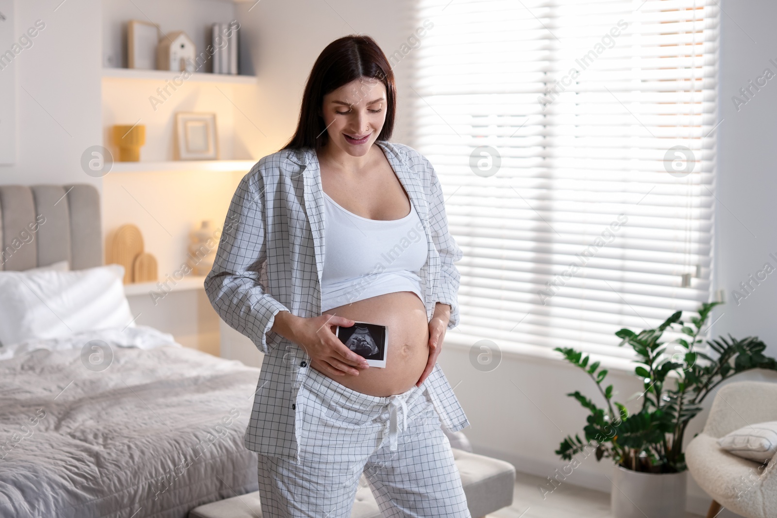 Photo of Beautiful pregnant woman with ultrasound scan at home