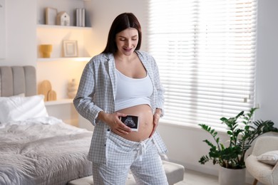 Beautiful pregnant woman with ultrasound scan at home