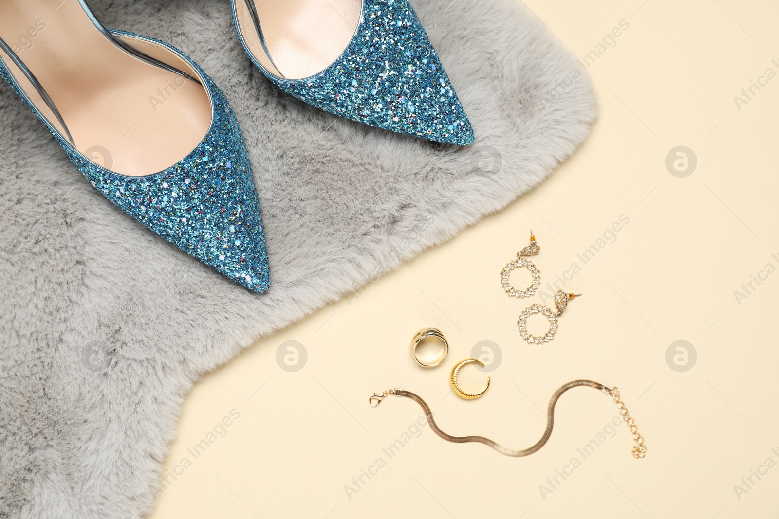 Photo of Fashionable composition with shiny high heeled shoes and accessories on beige background, flat lay