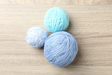 Photo of Balls of colorful yarn on wooden table, flat lay