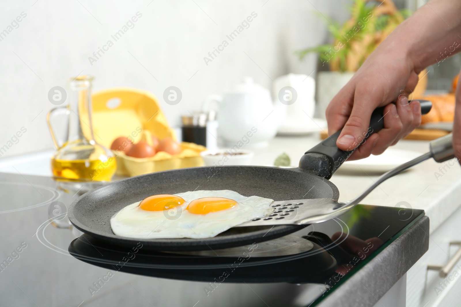 Photo of Man taking fried eggs from frying pan in kitchen, closeup