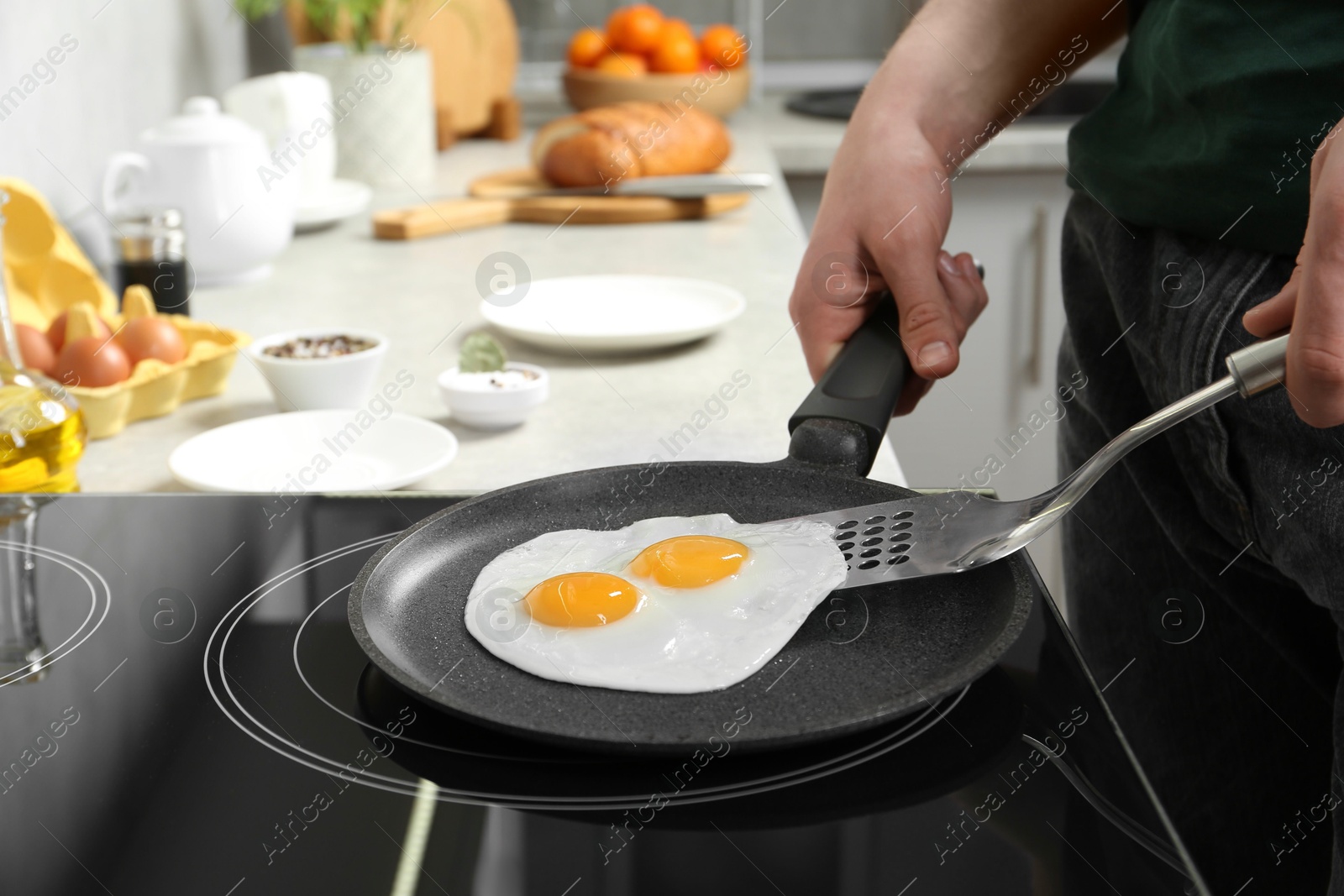 Photo of Man taking fried eggs from frying pan in kitchen, closeup