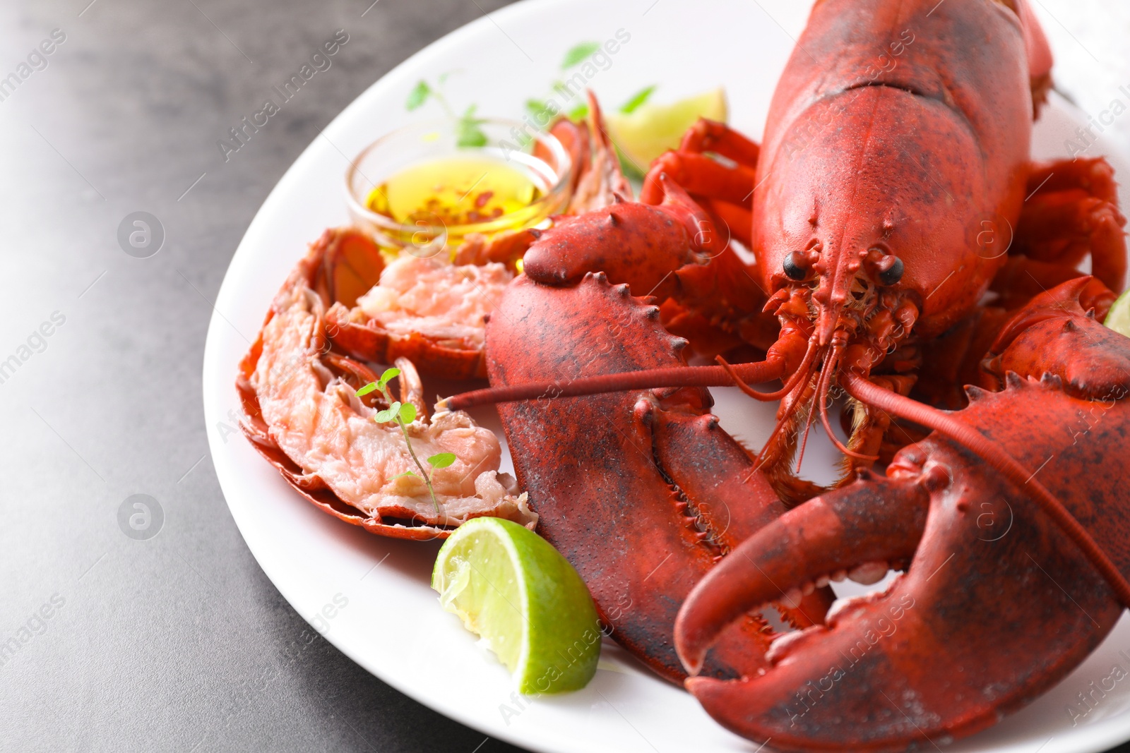 Photo of Delicious boiled lobster served on grey table, closeup