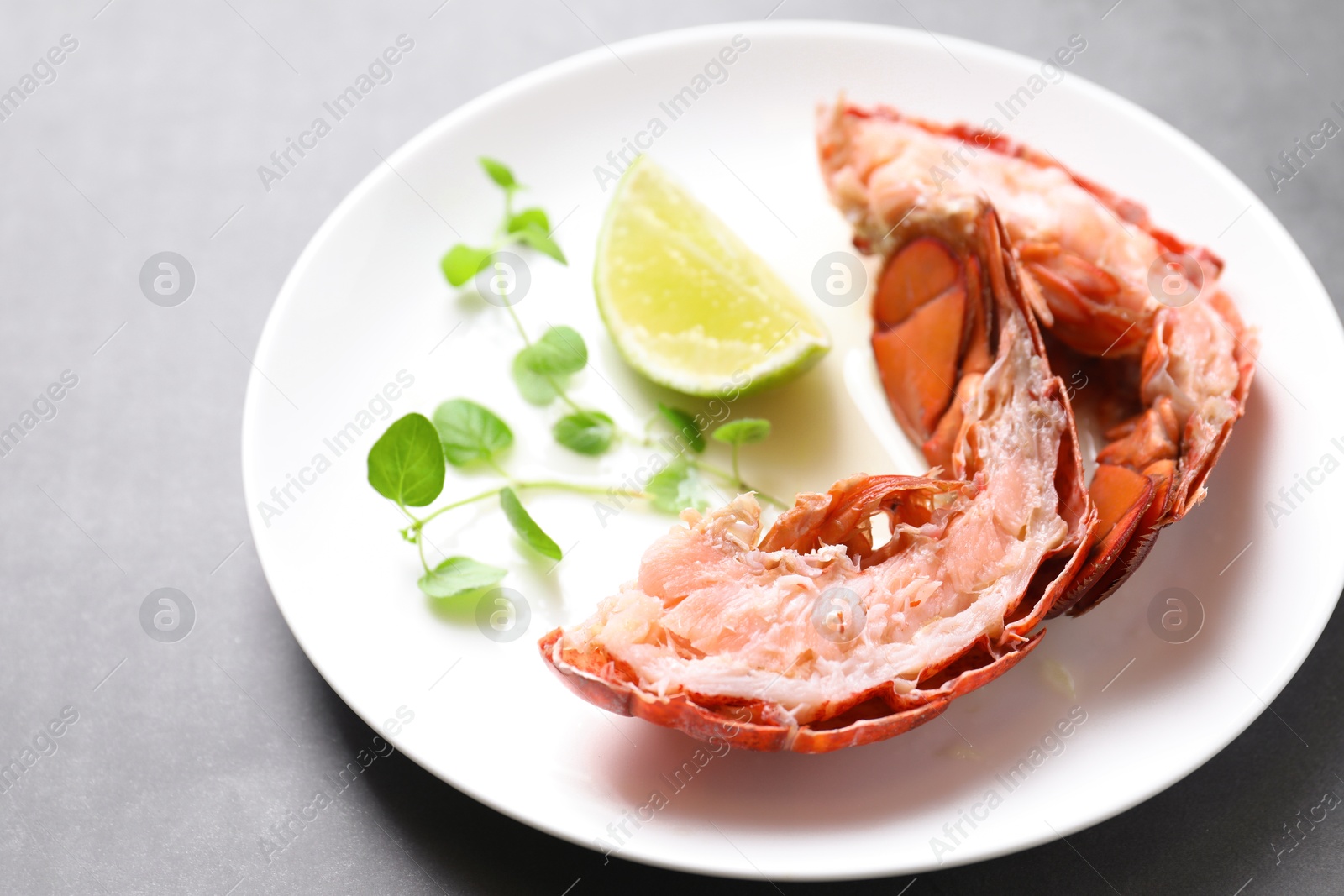 Photo of Delicious tail of boiled lobster served on grey table, closeup