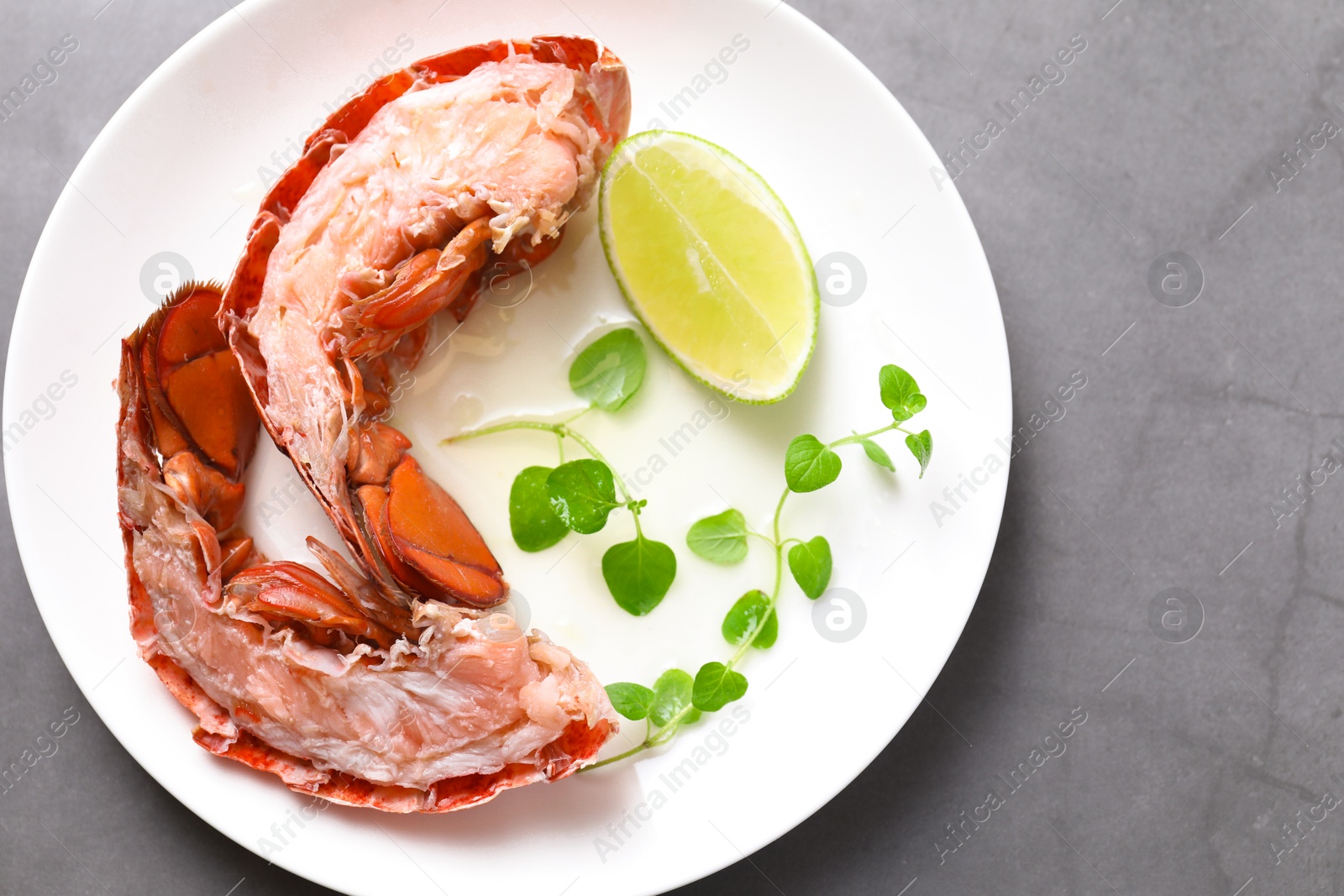 Photo of Delicious tail of boiled lobster served on grey table, top view