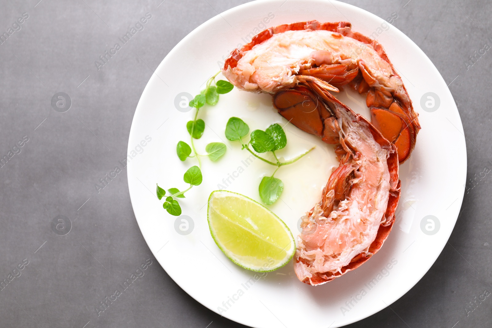 Photo of Delicious tail of boiled lobster served on grey table, top view