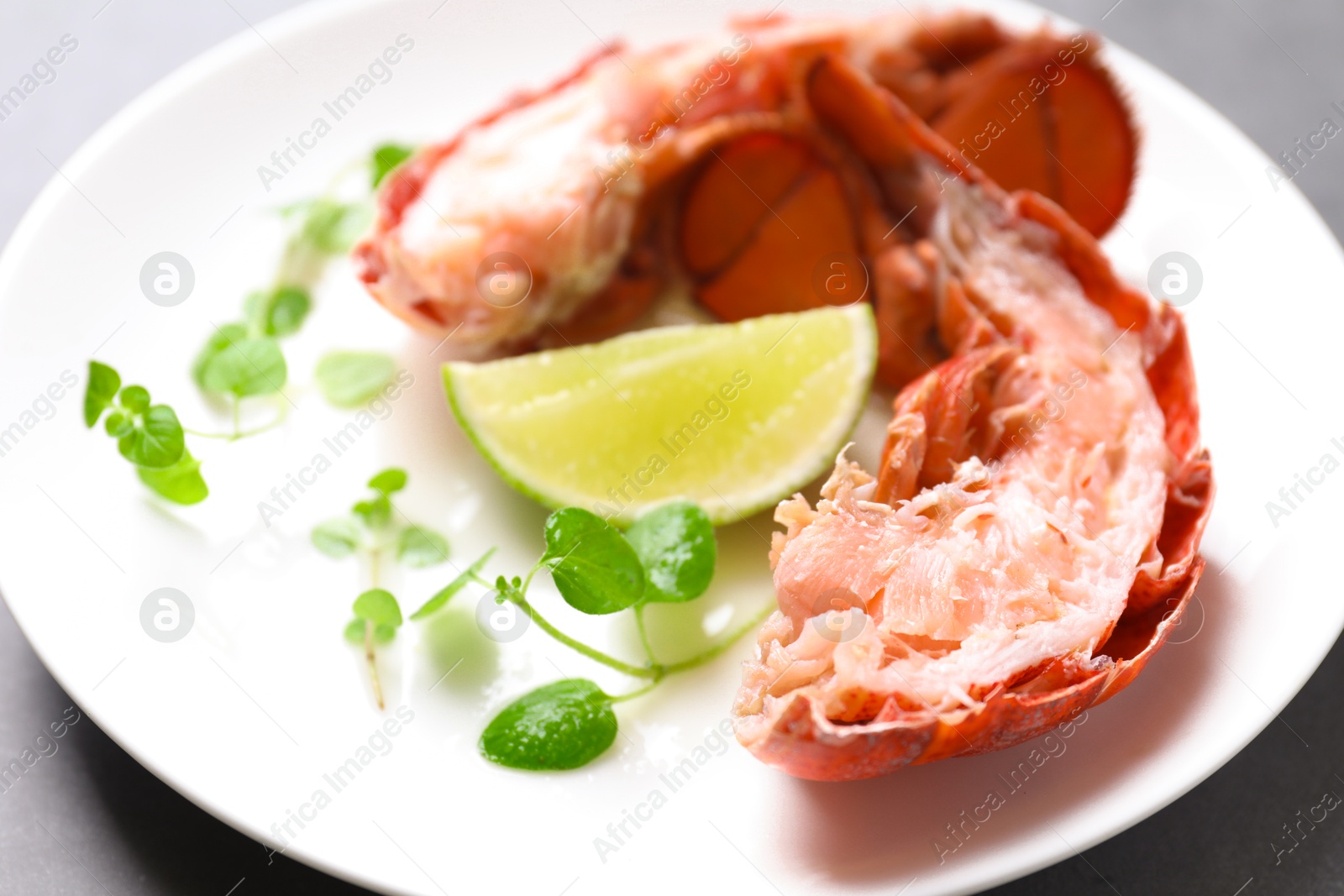 Photo of Delicious tail of boiled lobster served on grey table, closeup