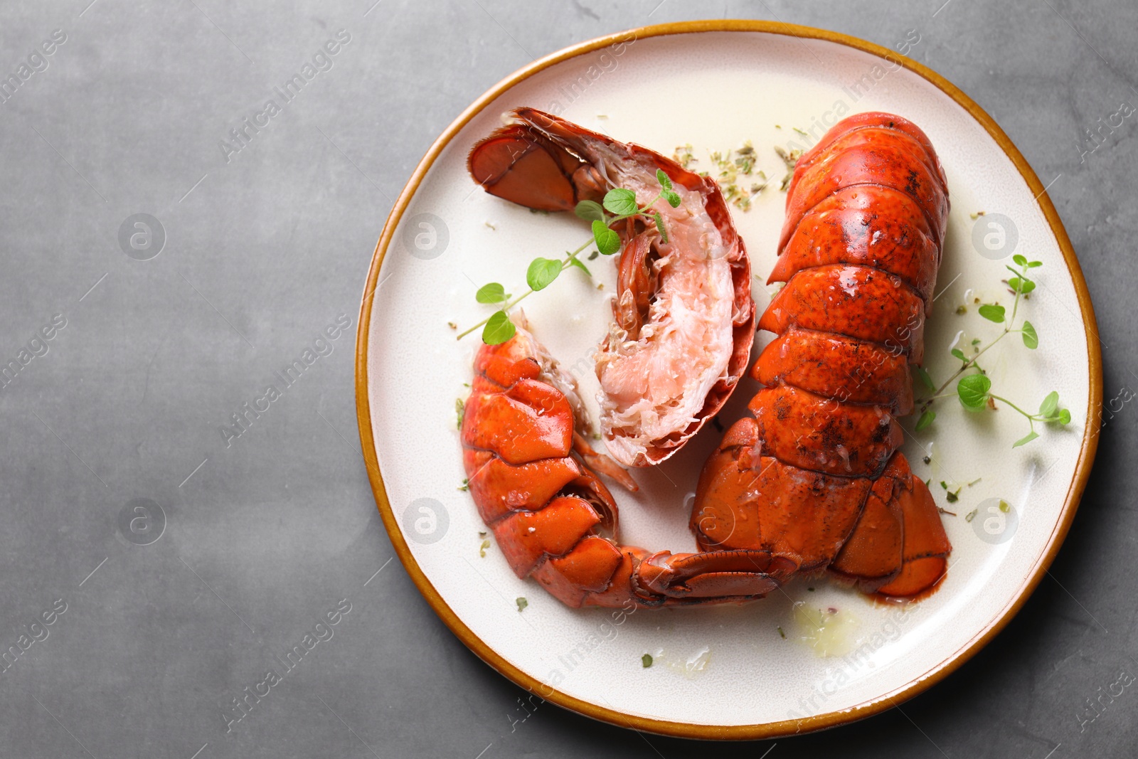 Photo of Delicious tails of boiled lobsters served on grey table, top view. Space for text