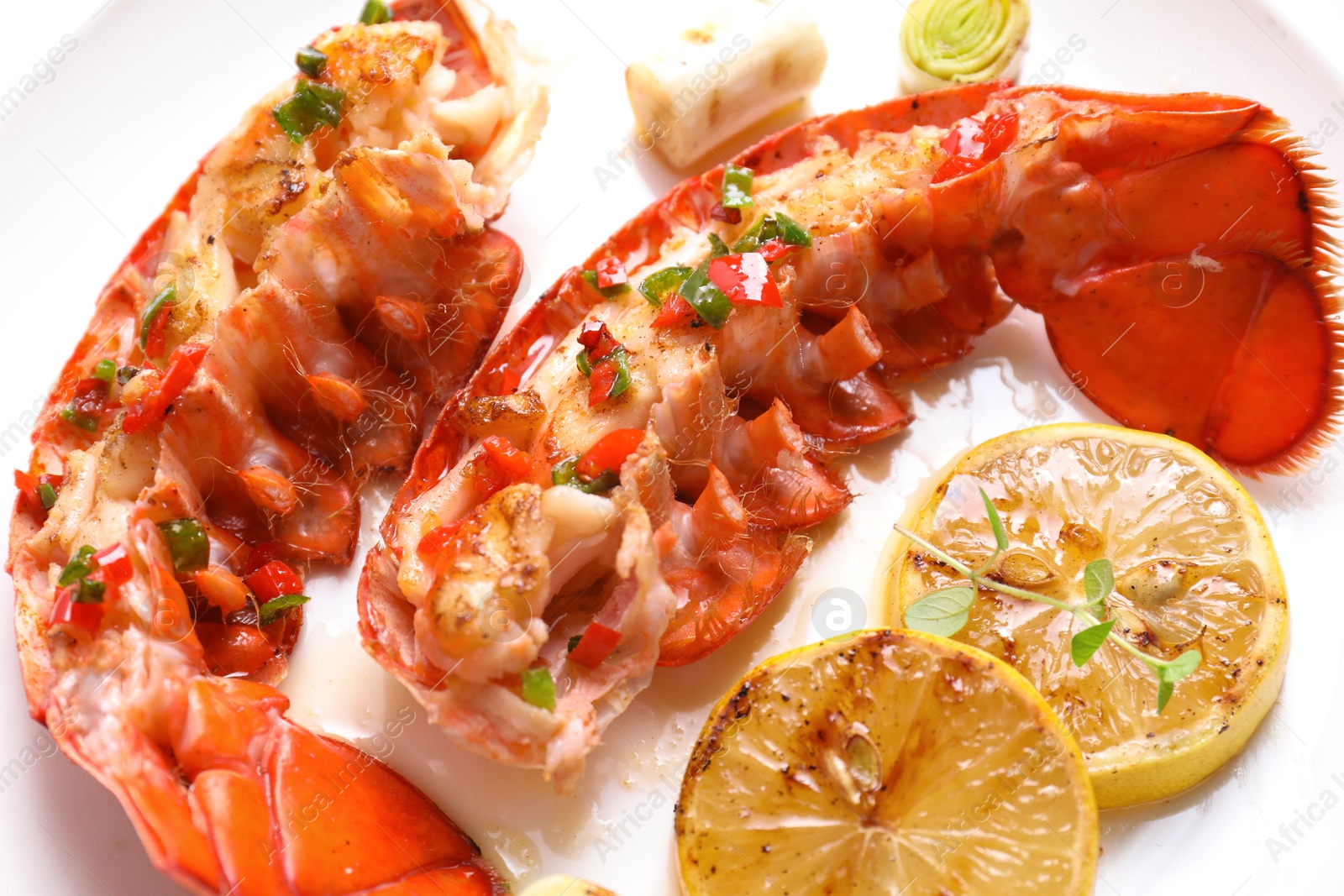 Photo of Delicious lobster tails with lemon, microgreens and green onion on white plate, closeup