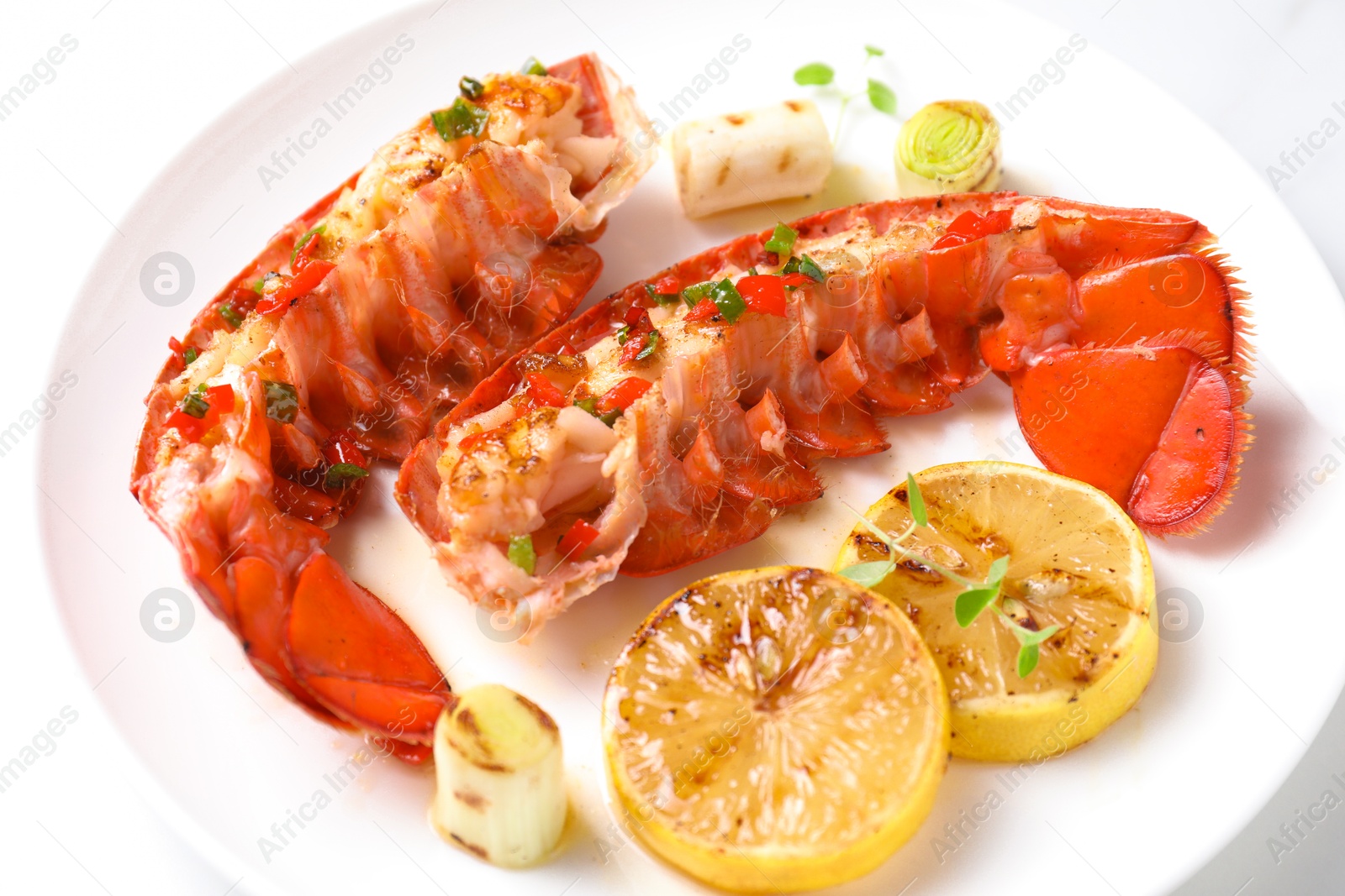 Photo of Delicious lobster tails with lemon, microgreens and green onion on white table, closeup