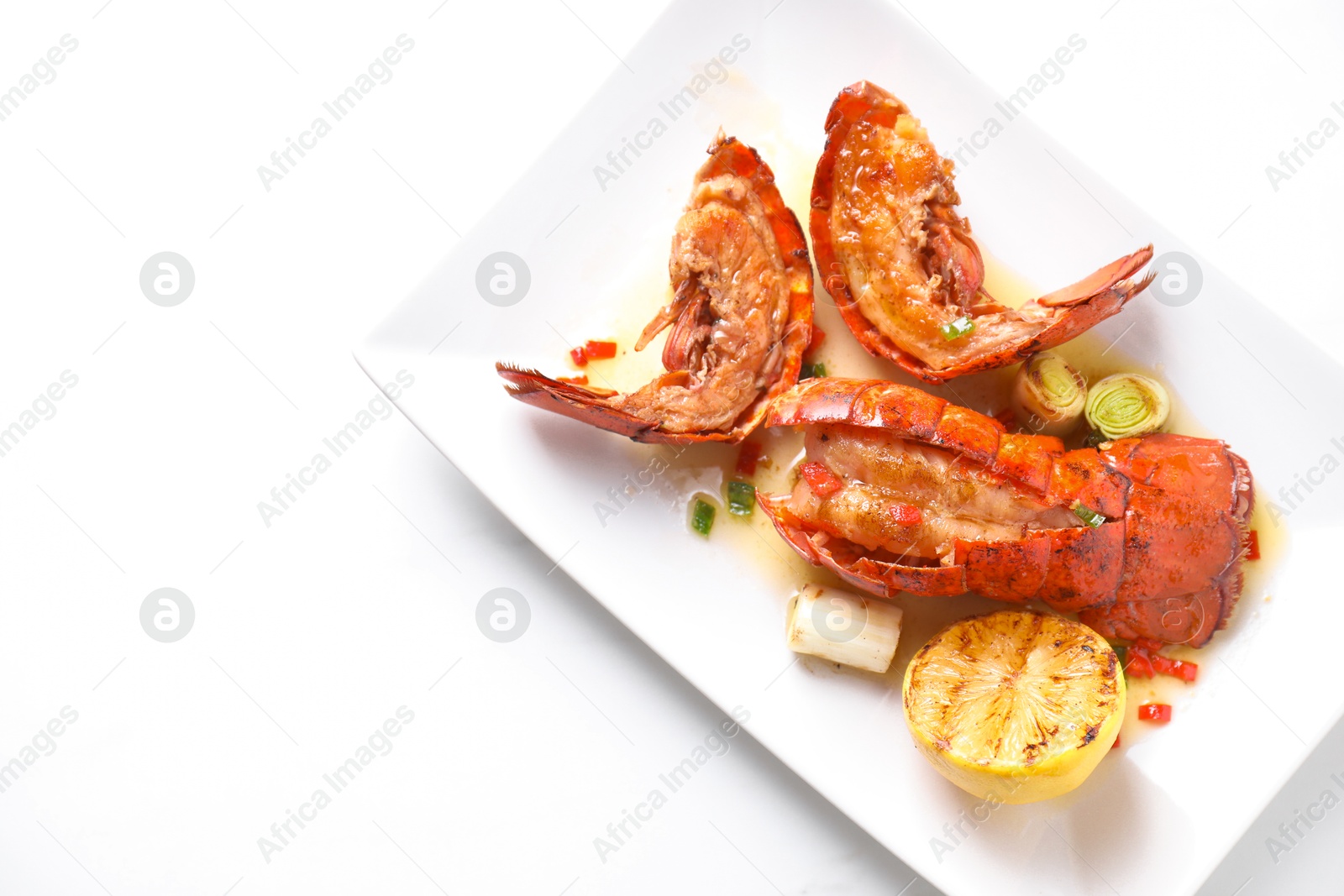 Photo of Delicious lobster tails with lemon and green onion on white table, top view. Space for text