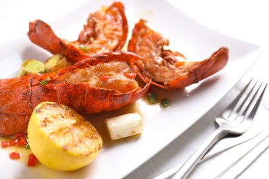 Photo of Delicious lobster tails with lemon and green onion on white table, closeup