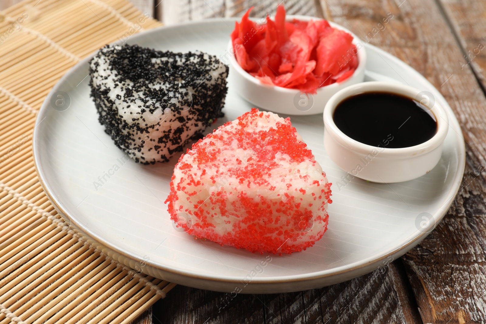 Photo of Tasty tobiko onigiri (Japanese rice balls) served on wooden table, closeup