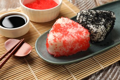 Photo of Tasty tobiko onigiri (Japanese rice balls) served on wooden table, closeup