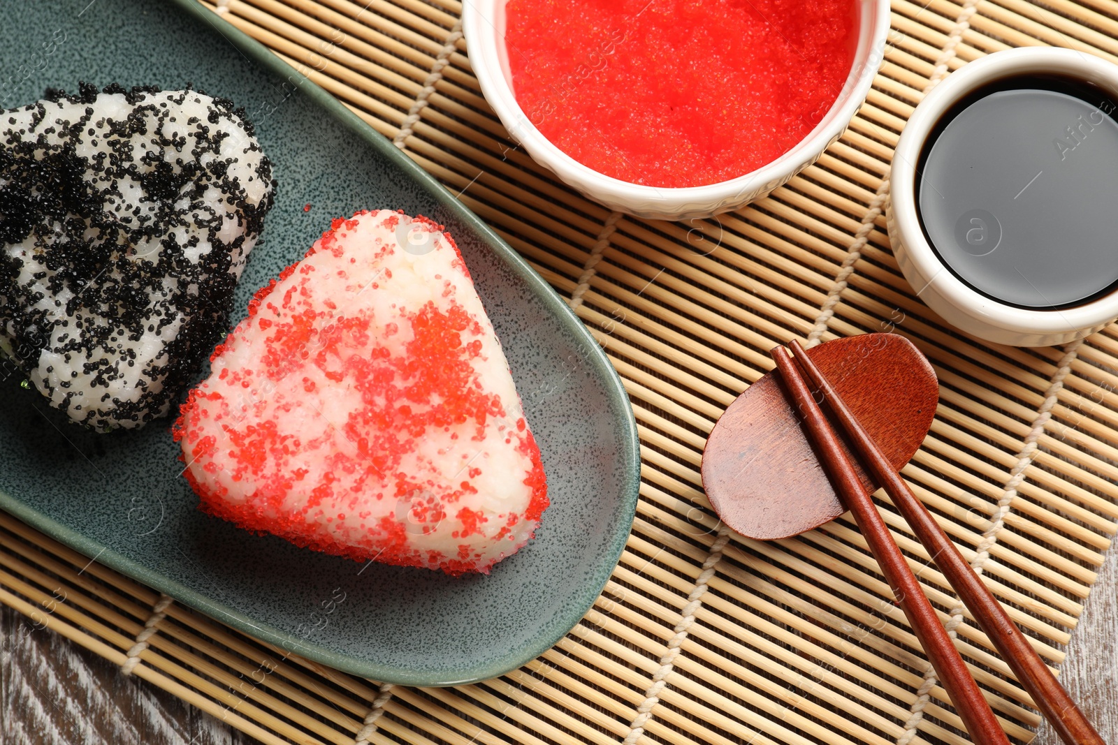 Photo of Tasty tobiko onigiri (Japanese rice balls) served on table, flat lay