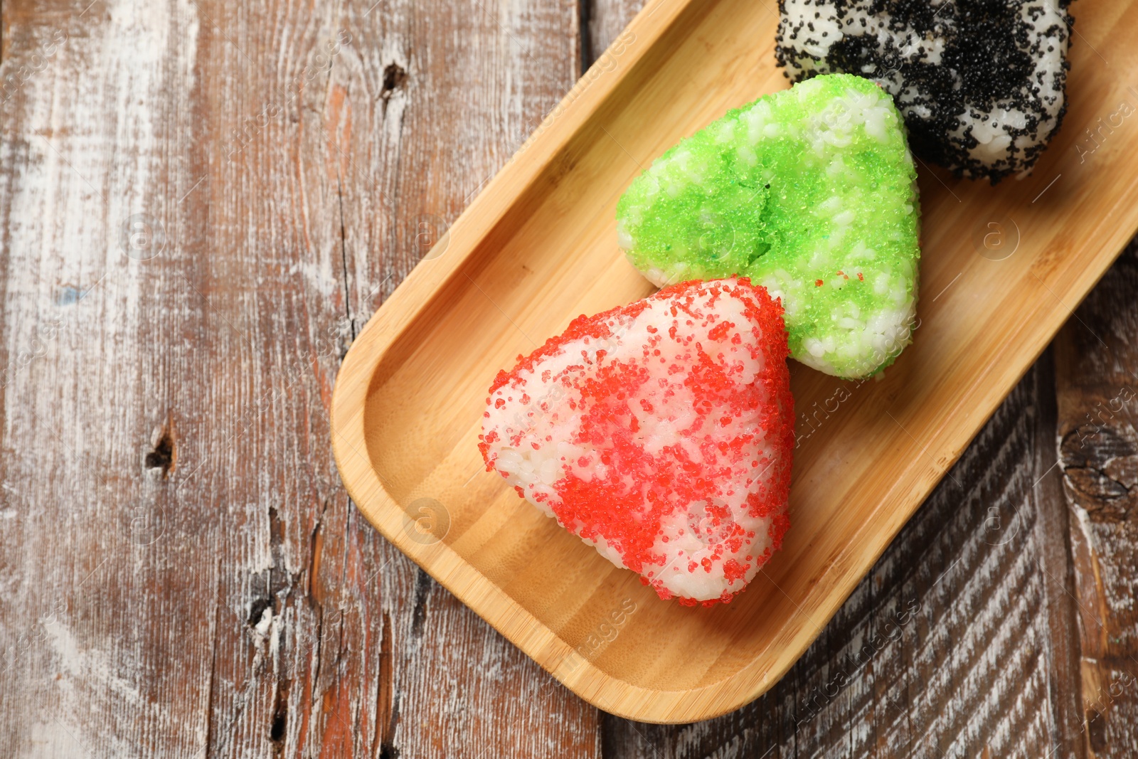 Photo of Tasty tobiko onigiri (Japanese rice balls) served on wooden table, top view