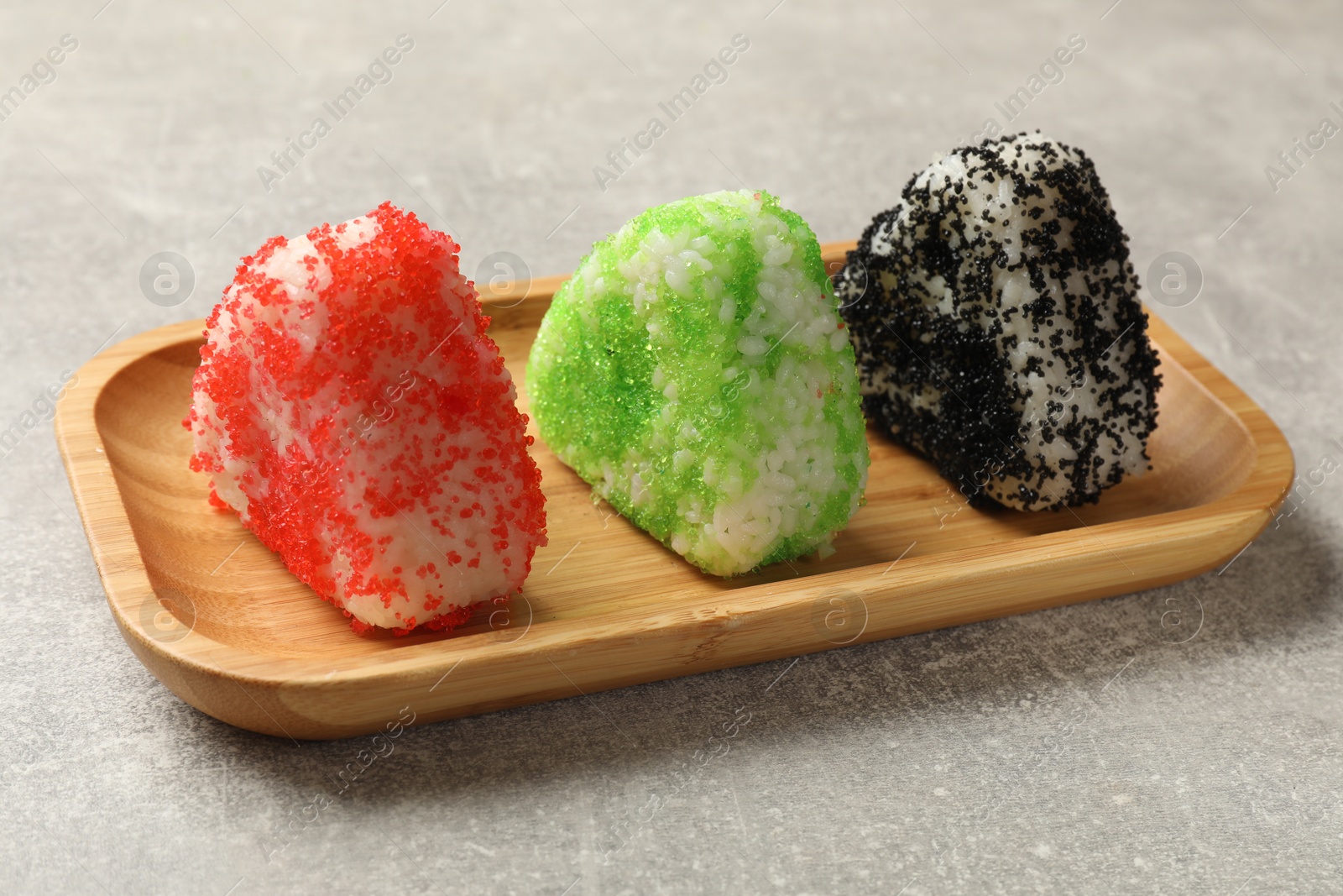 Photo of Tasty tobiko onigiri (Japanese rice balls) served on grey table, closeup