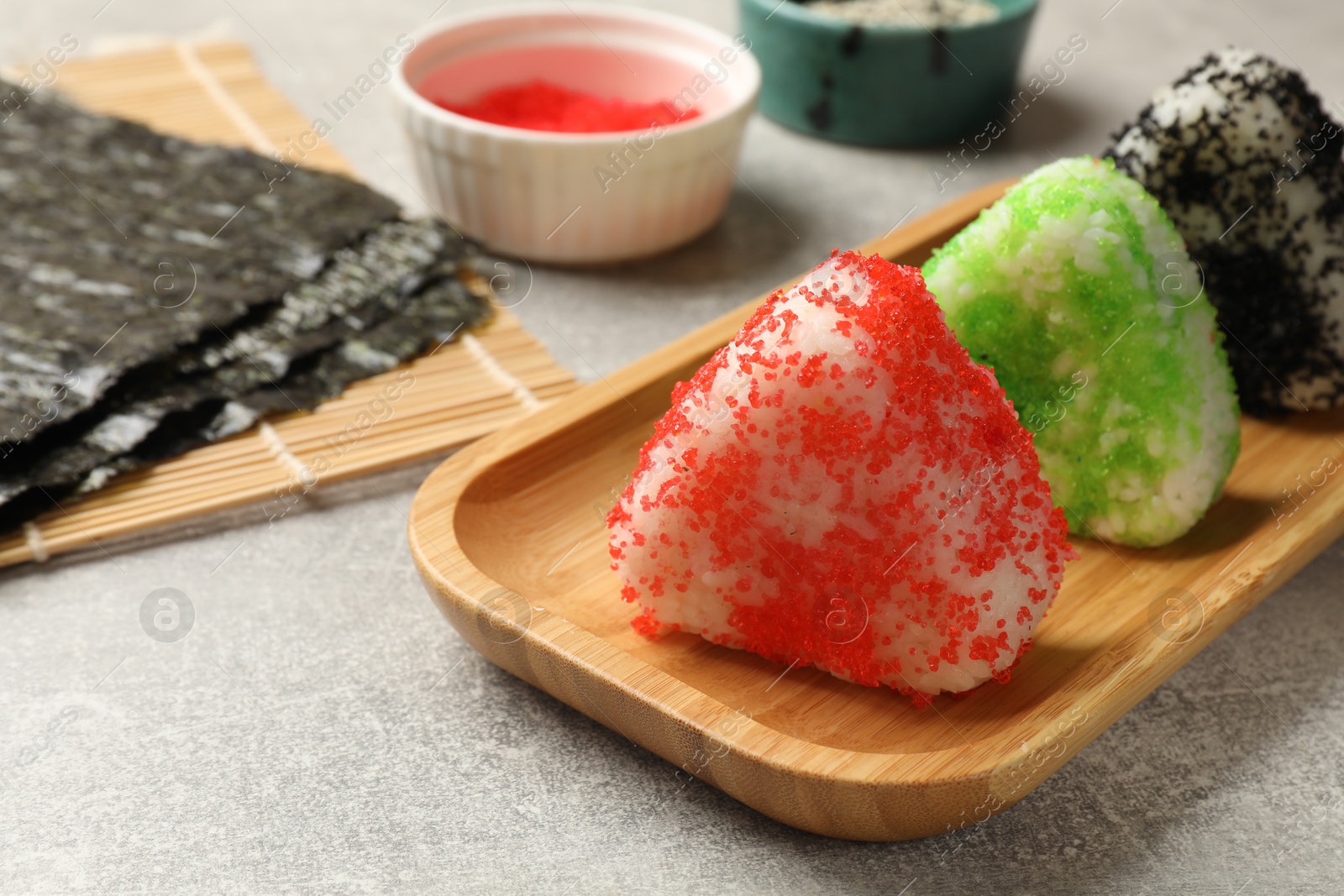 Photo of Tasty tobiko onigiri (Japanese rice balls) served on grey table, closeup