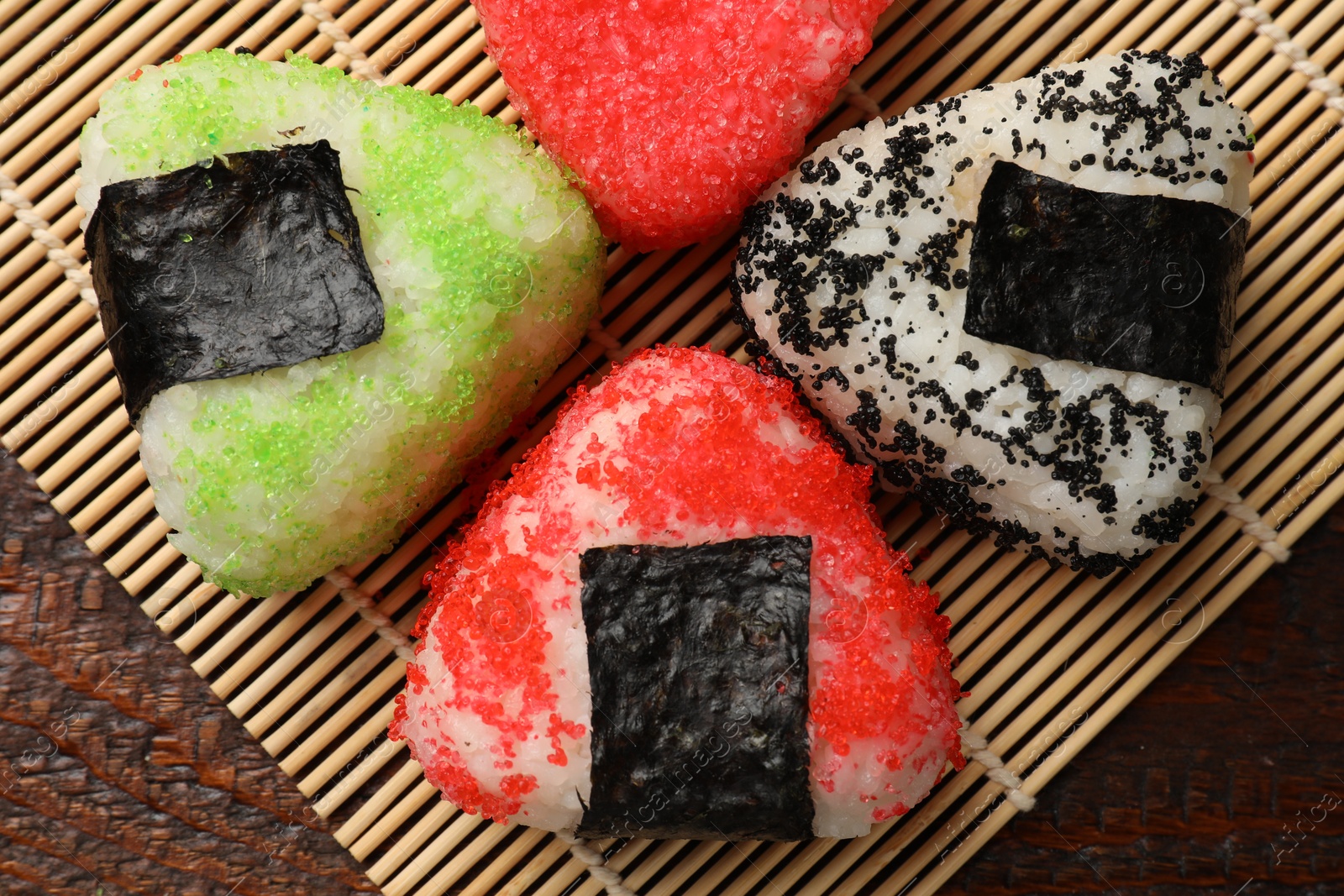 Photo of Tasty tobiko onigiri (Japanese rice balls) served on wooden table, top view