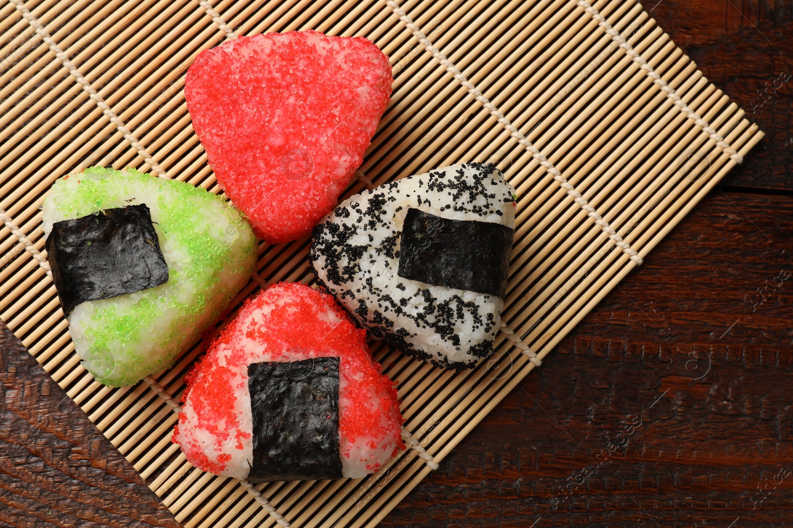 Photo of Tasty tobiko onigiri (Japanese rice balls) served on wooden table, top view