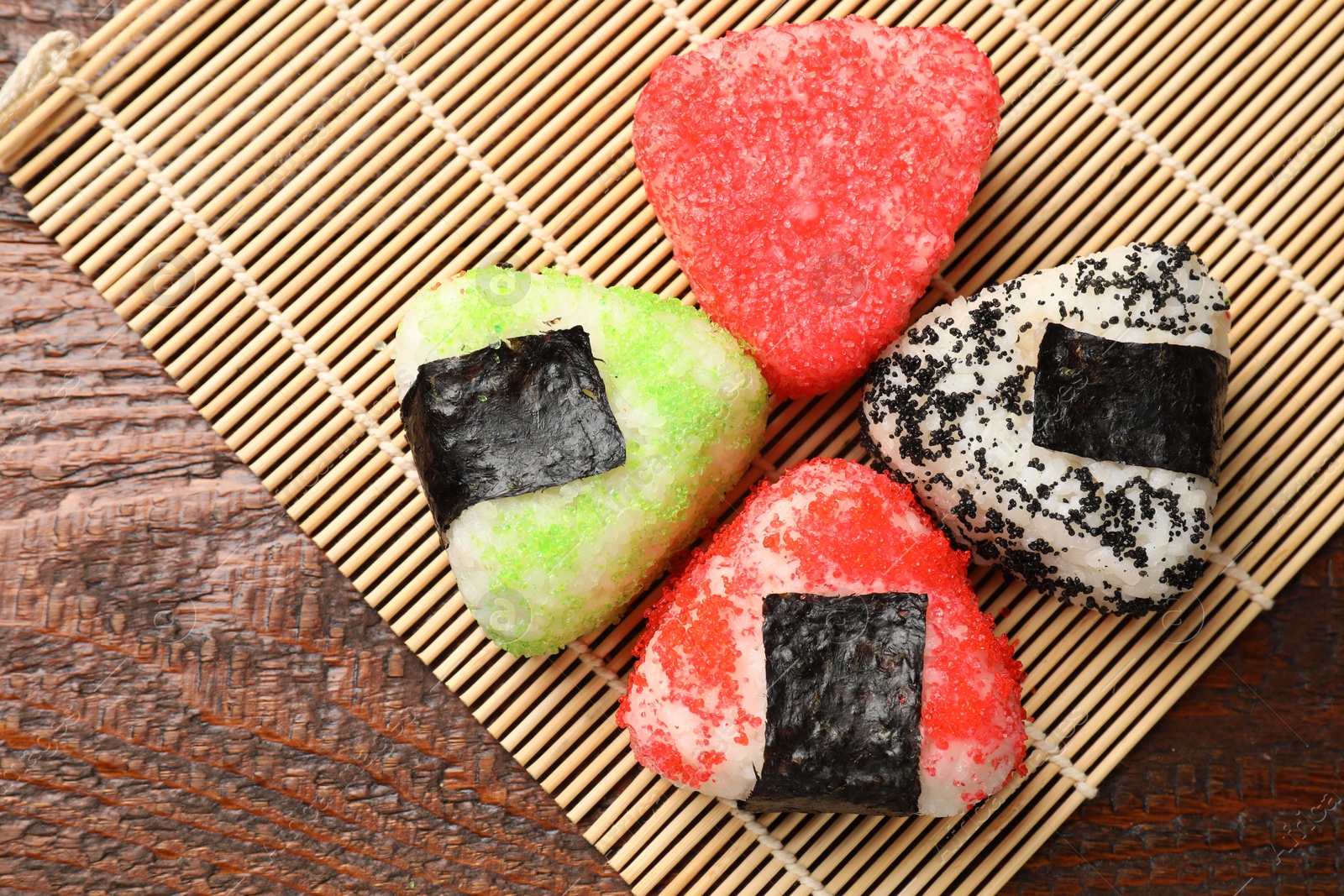 Photo of Tasty tobiko onigiri (Japanese rice balls) served on wooden table, top view