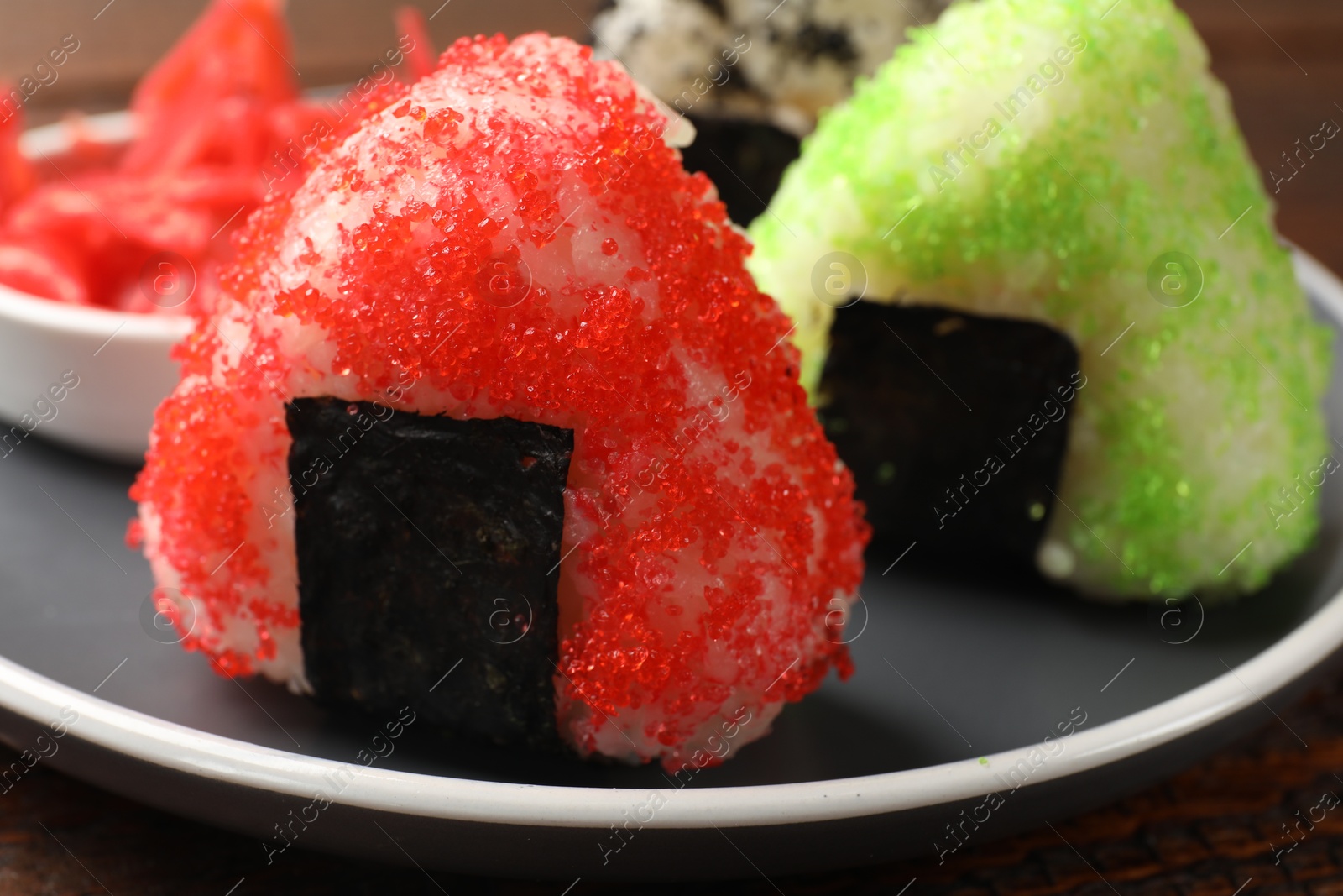 Photo of Tasty tobiko onigiri (Japanese rice balls) served on wooden table, closeup