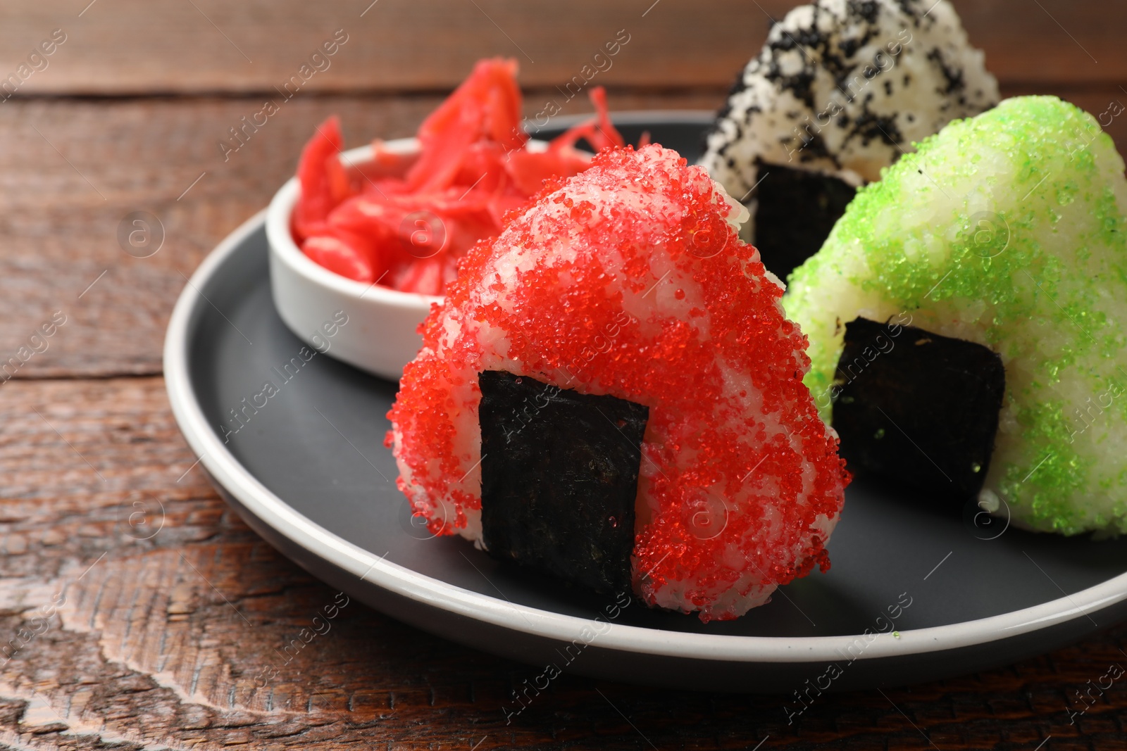 Photo of Tasty tobiko onigiri (Japanese rice balls) served on wooden table, closeup