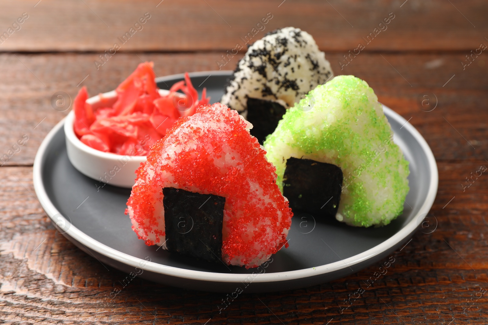 Photo of Tasty tobiko onigiri (Japanese rice balls) served on wooden table, closeup