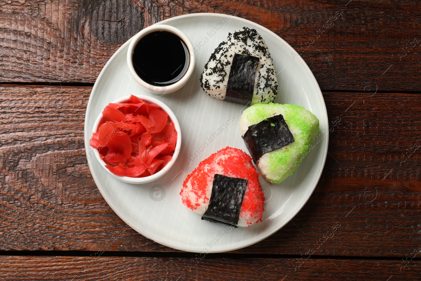 Photo of Tasty tobiko onigiri (Japanese rice balls) served on wooden table, top view