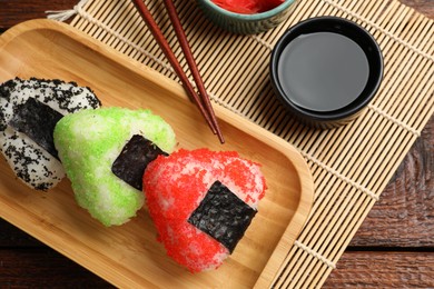 Photo of Tasty tobiko onigiri (Japanese rice balls) served on wooden table, flat lay