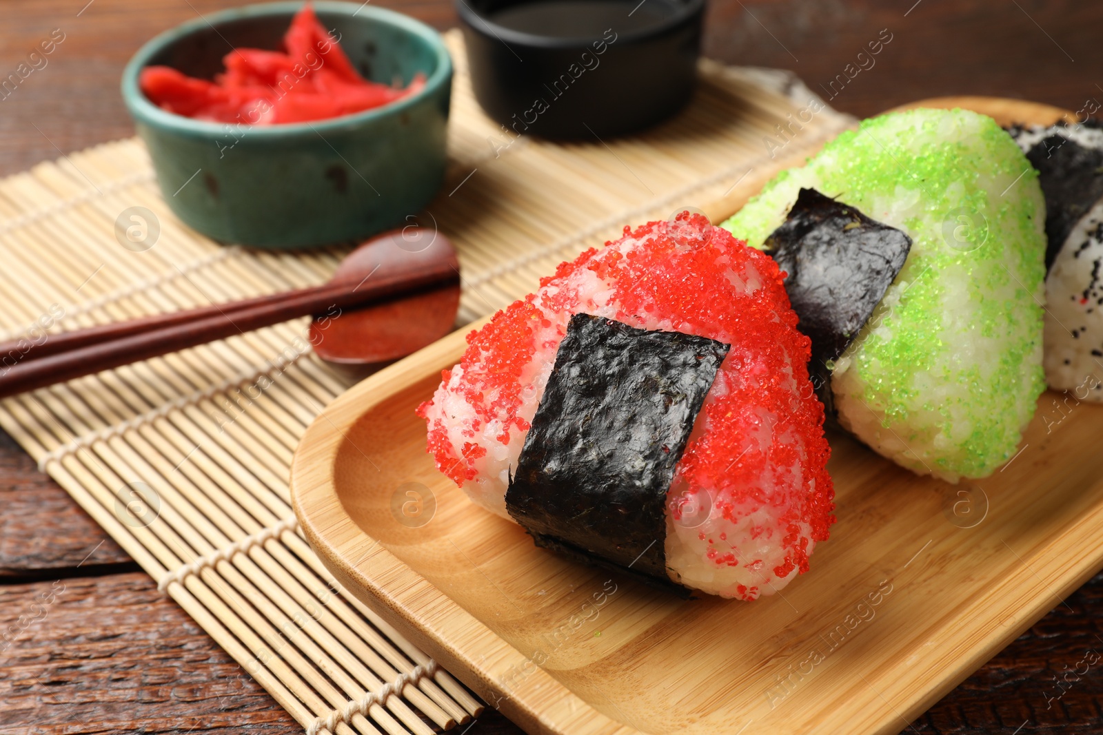 Photo of Tasty tobiko onigiri (Japanese rice balls) served on wooden table, closeup