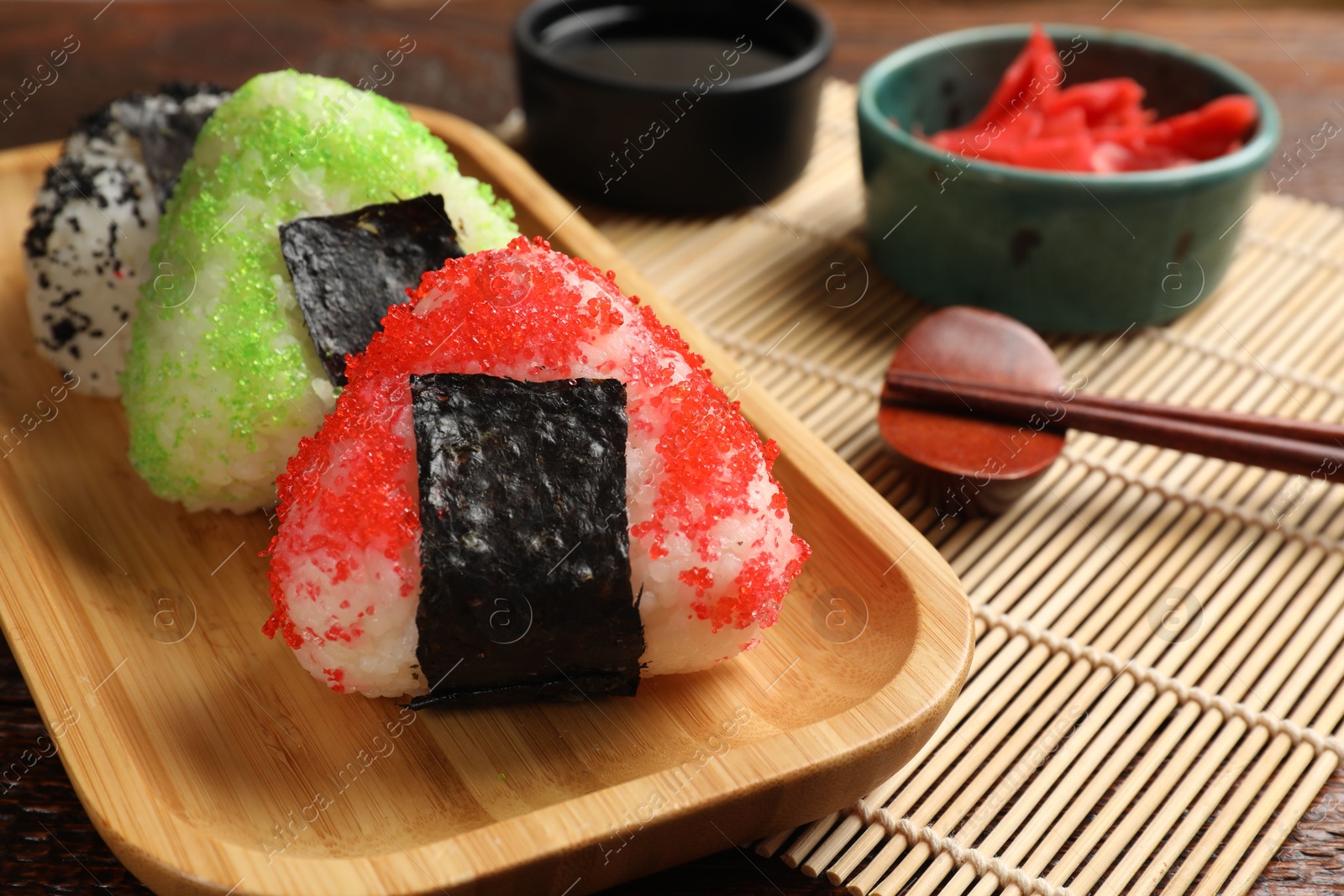 Photo of Tasty tobiko onigiri (Japanese rice balls) served on wooden table, closeup