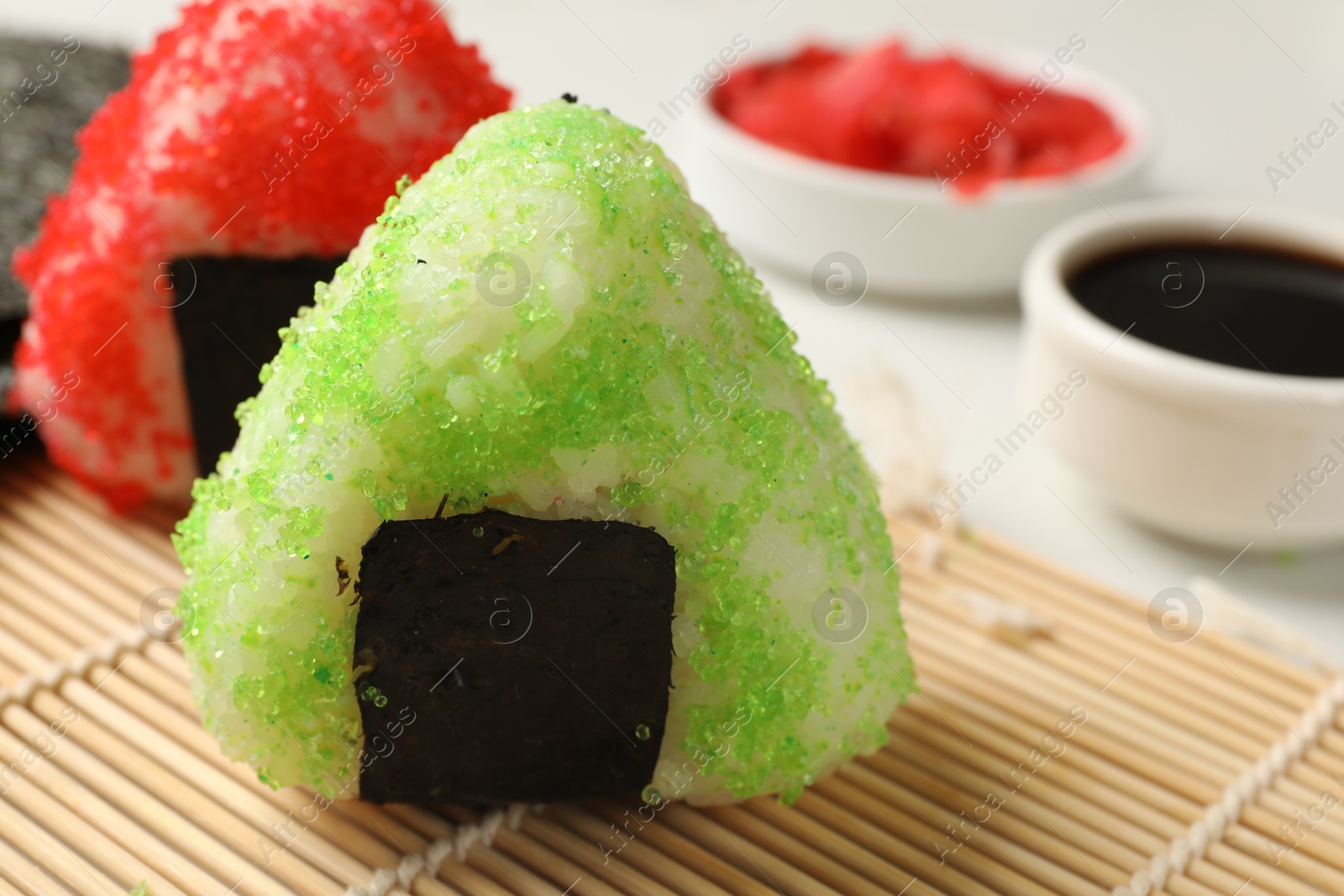 Photo of Tasty tobiko onigiri (Japanese rice balls) served on light table, closeup