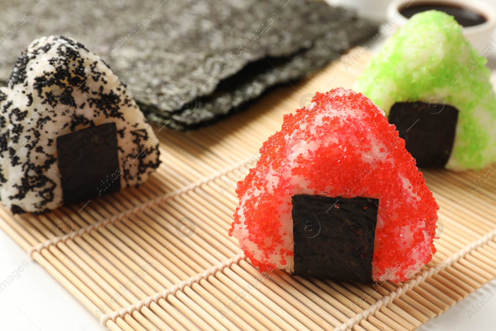 Photo of Tasty tobiko onigiri (Japanese rice balls) served on light table, closeup