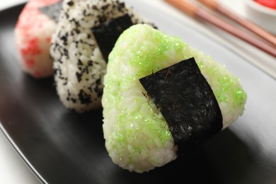 Photo of Tasty tobiko onigiri (Japanese rice balls) served on light table, closeup