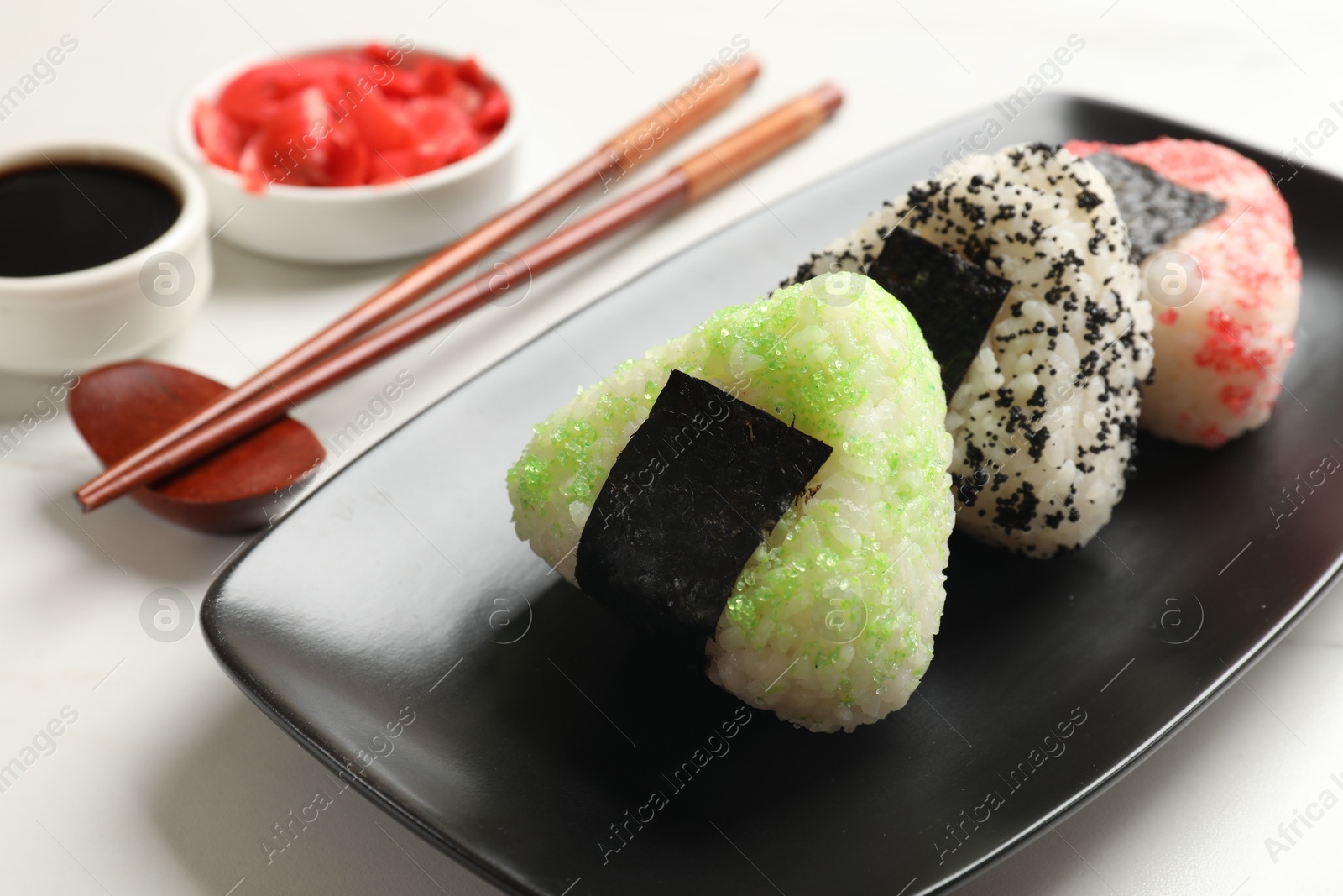 Photo of Tasty tobiko onigiri (Japanese rice balls) served on white table, closeup