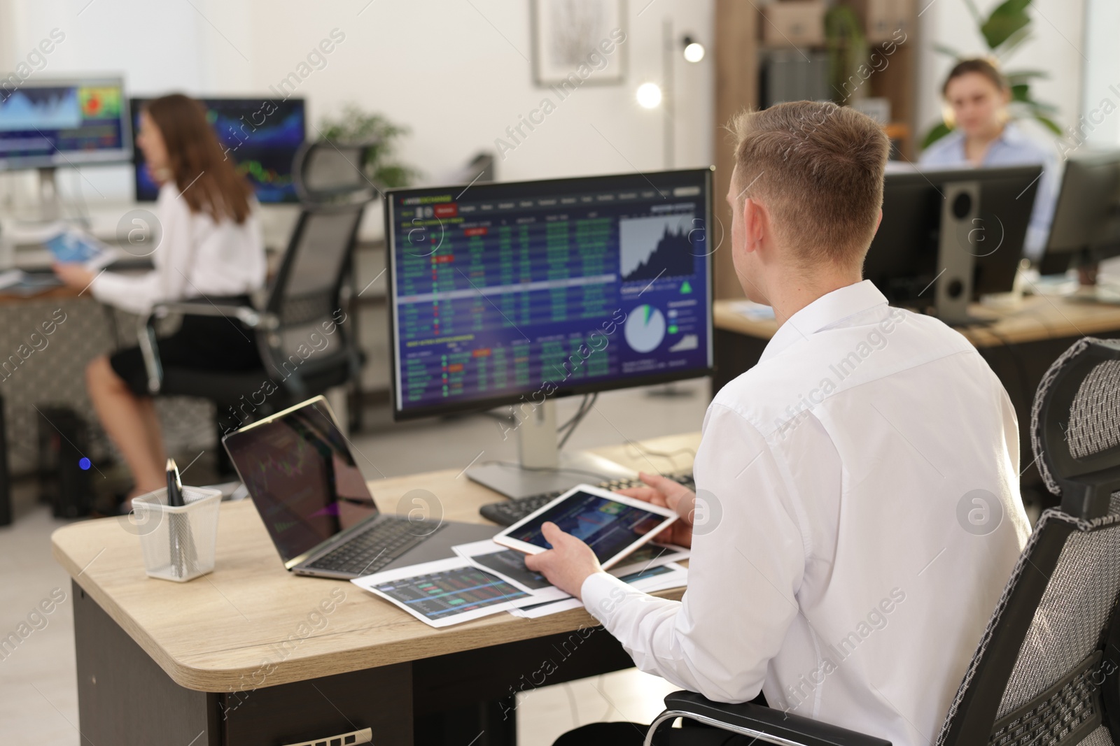 Photo of Stock exchange. Man working at desk in office, back view