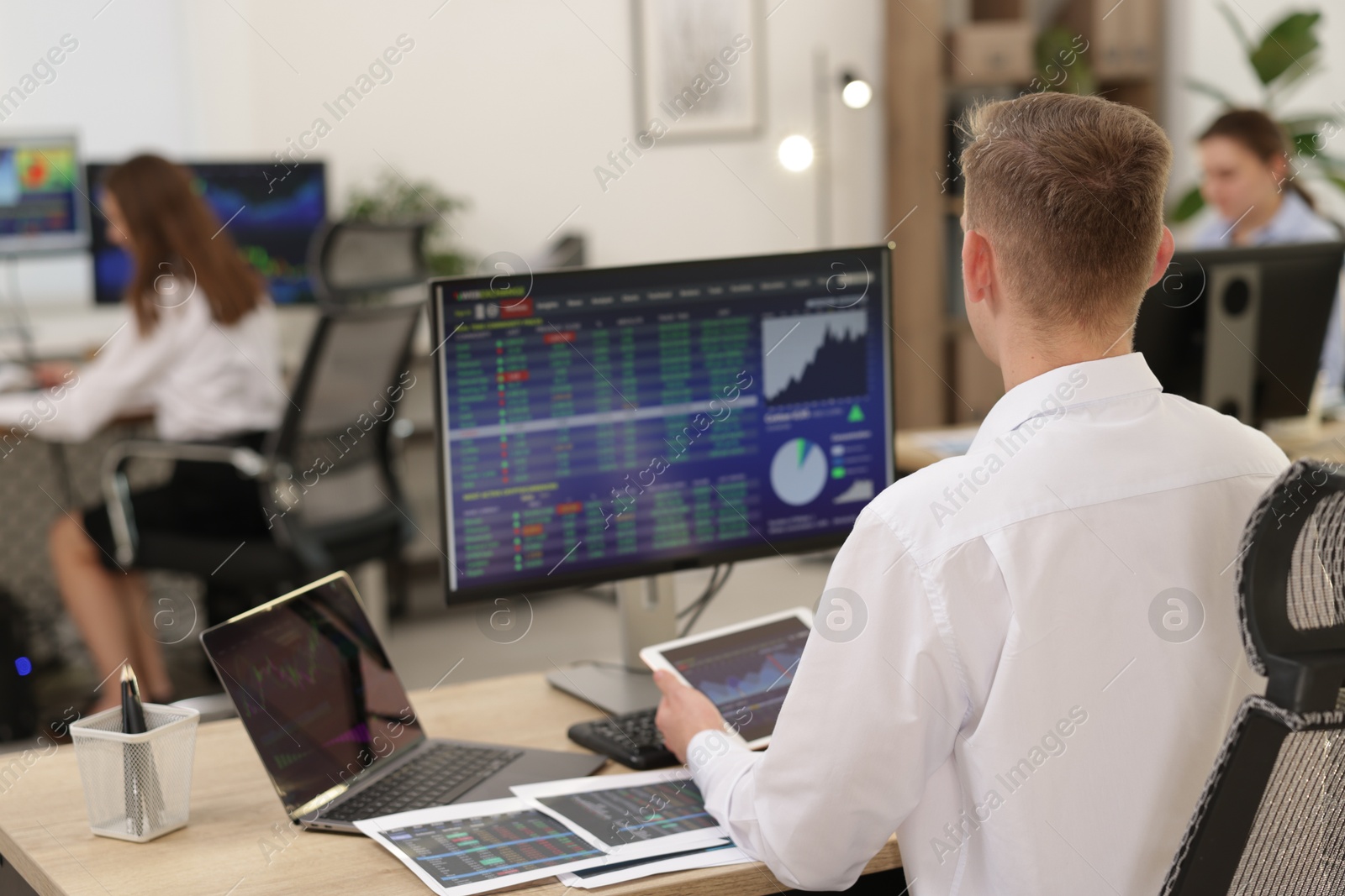 Photo of Stock exchange. Man working at desk in office, back view