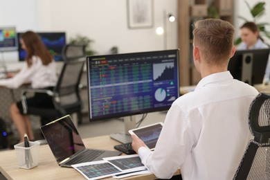 Photo of Stock exchange. Man working at desk in office, back view